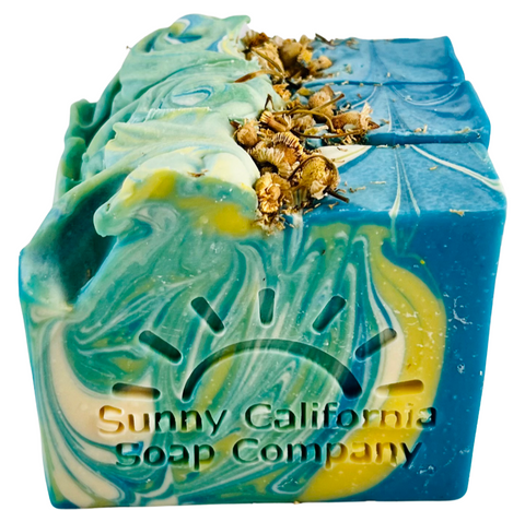 Soap bar swirled in blue, yellow and white with dried chamomile flowers on top. 